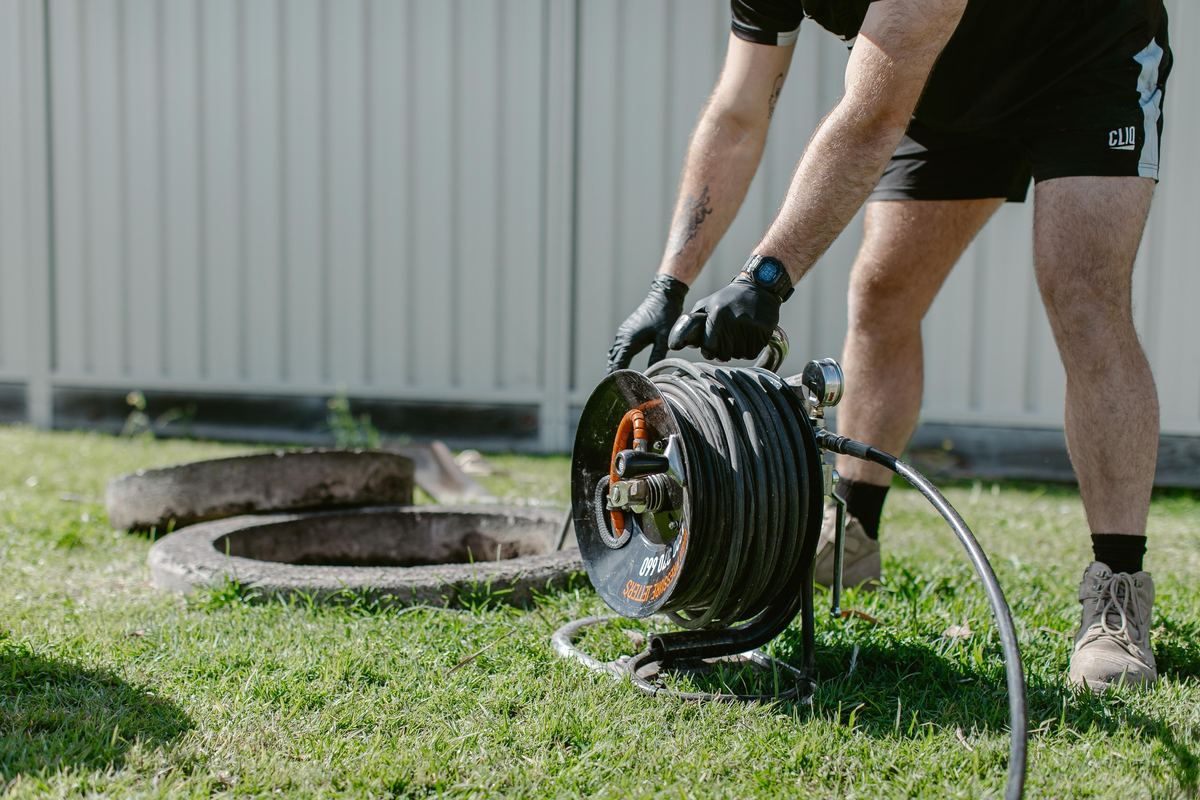 Plumbers clearing a stormwater line in a backyard